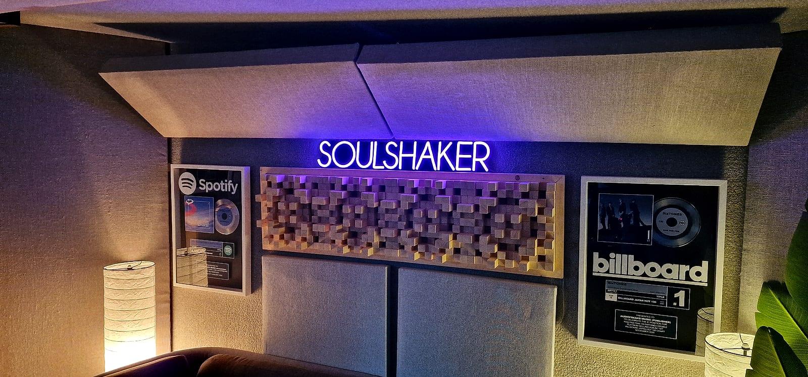 The studio with a Soulshaker neon sign and framed Billboard and Spotify plaques