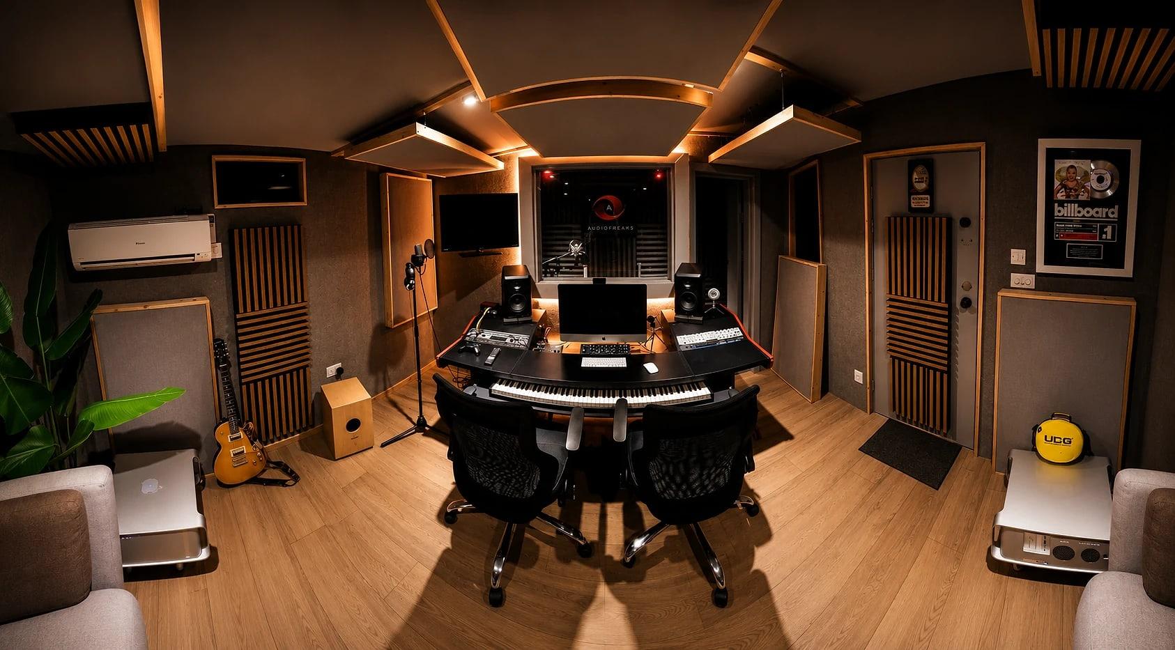 The studio desk face-on, keys and monitors, looking through the glass into the Audiofreaks vocal booth